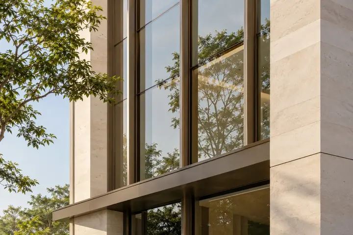 Bronze-framed glazing and warm stone on a contemporary building facade